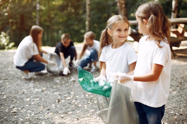 Foto gratuita los niños recogen basura en bolsas de basura en el parque