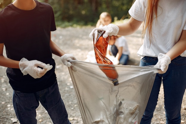 Foto gratuita los niños recogen basura en bolsas de basura en el parque