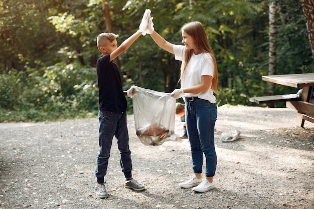 Foto gratuita los niños recogen basura en bolsas de basura en el parque