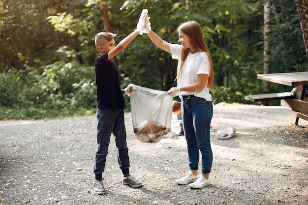 Los niños recogen basura en bolsas de basura en el parque