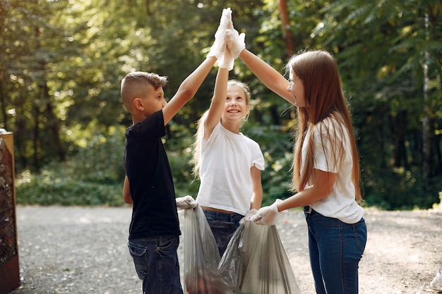 Los niños recogen basura en bolsas de basura en el parque