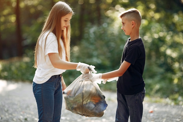 Los niños recogen basura en bolsas de basura en el parque