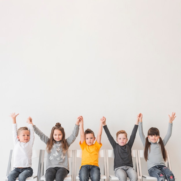 Foto gratuita niños sentados con las manos en alto