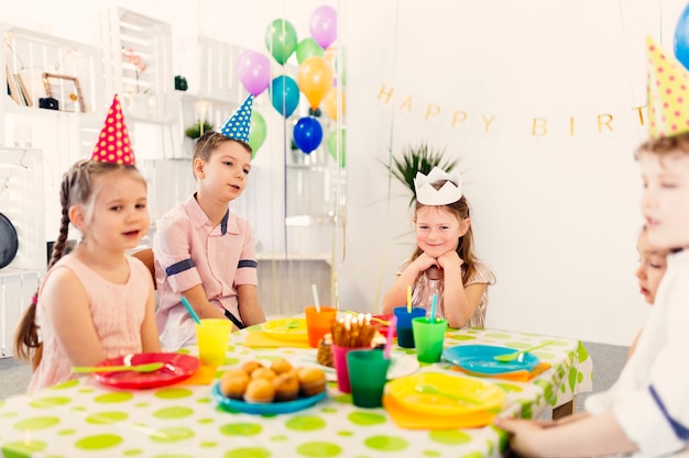 Niños sentados a la mesa en cumpleaños