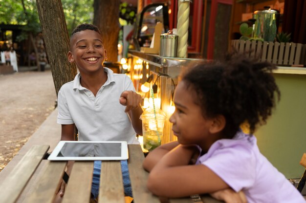 Niños sentados a la mesa con tableta de tiro medio