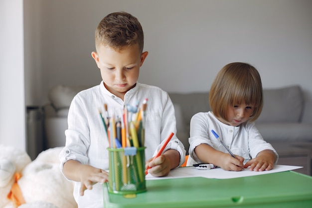 Niños sentados en la mesa verde y dibujando
