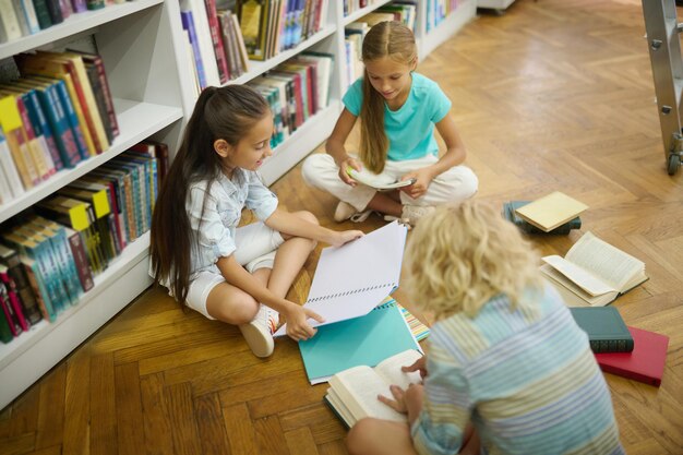 Niños sentados en el suelo con libros y cuadernos.