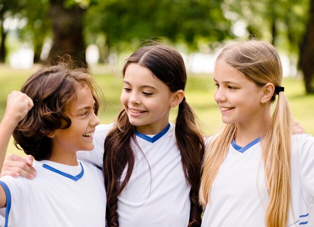 Niños sonriendo después de ganar un partido de fútbol.