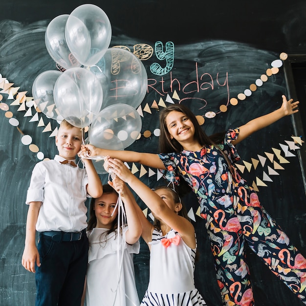 Niños sonrientes con globos en la fiesta de cumpleaños