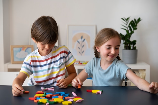 Foto gratuita niños sonrientes haciendo rompecabezas juntos vista frontal