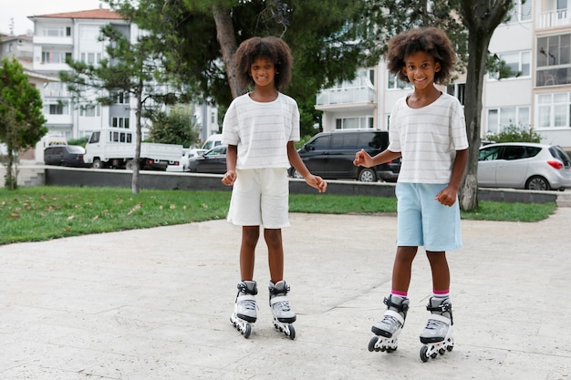 Foto gratuita niños sonrientes con patines de ruedas tiro completo