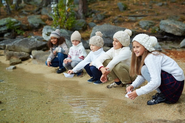 Niños sonrientes sentados junto al agua