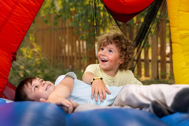 Niños sonrientes de tiro completo jugando en la casa de rebote