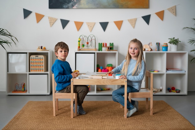 Niños sonrientes de tiro completo sentados en la mesa