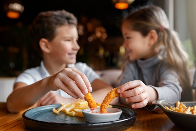 Niños sonrientes de tiro medio comiendo juntos