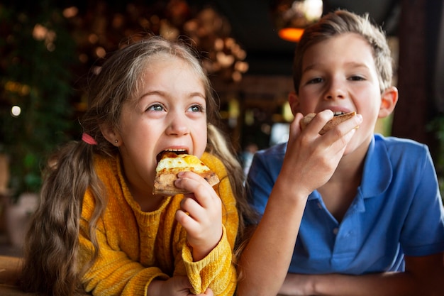 Niños sonrientes de tiro medio comiendo pizza