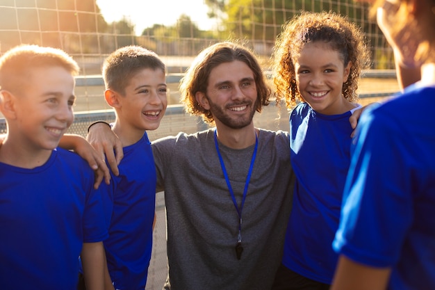 Foto gratuita niños sonrientes de tiro medio con entrenador