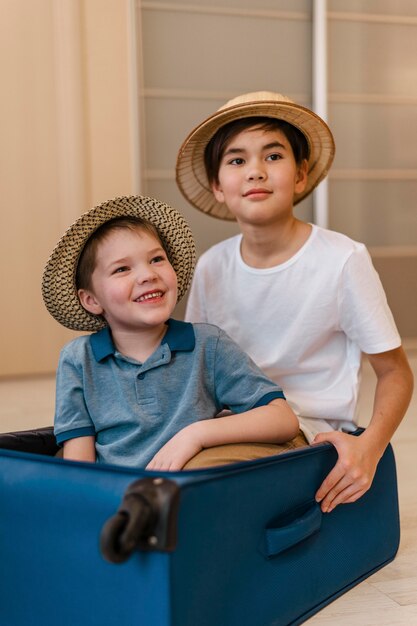 Foto gratuita niños sonrientes de tiro medio sentados en el equipaje