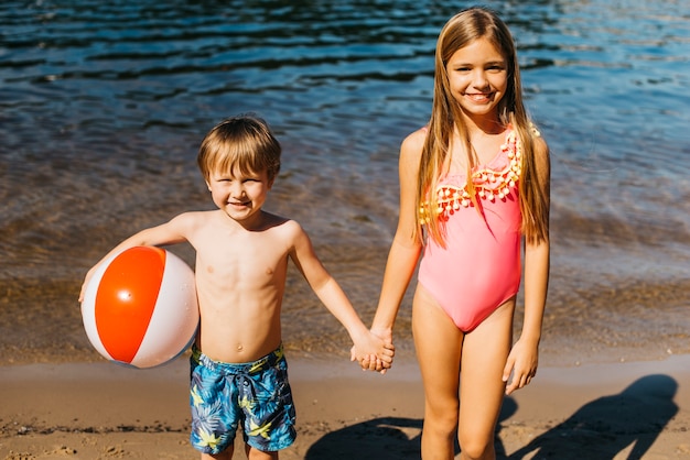 Niños sonrientes tomados de la mano en la playa