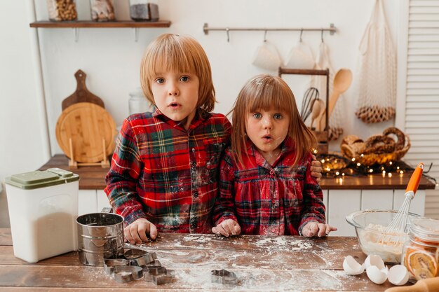 Niños sorprendidos haciendo galletas de Navidad juntos