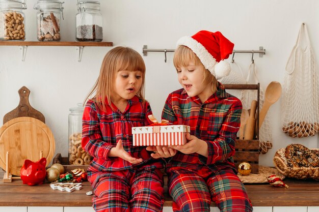 Niños sosteniendo juntos un regalo de navidad