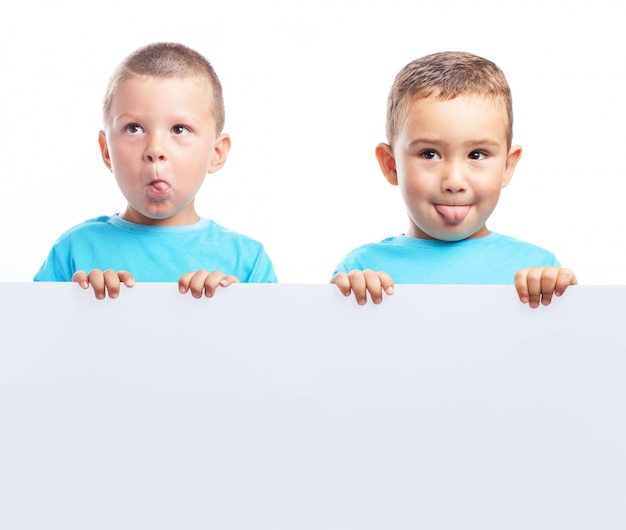 Foto gratuita niños sujetando una pancarta en blanco mientras ponen caras raras