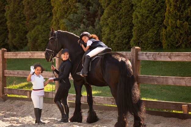 Niños de tiro completo aprendiendo a montar a caballo.