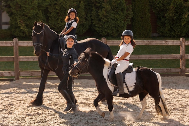 Foto gratuita niños de tiro completo aprendiendo a montar a caballo.