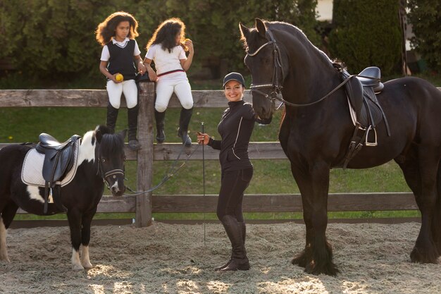 Foto gratuita niños de tiro completo aprendiendo a montar a caballo.