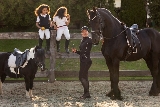 Niños de tiro completo aprendiendo a montar a caballo.