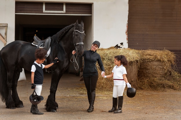 Niños de tiro completo aprendiendo a montar a caballo.