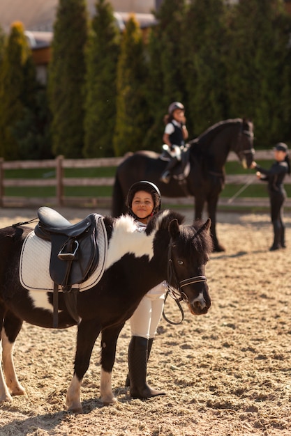 Niños de tiro completo aprendiendo a montar a caballo.