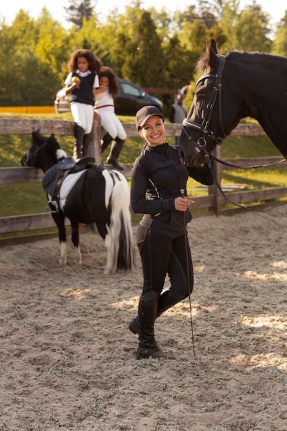 Foto gratuita niños de tiro completo aprendiendo a montar a caballo.
