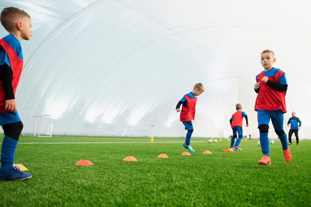 Foto gratuita niños de tiro completo en el campo de fútbol