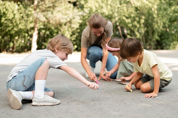 Niños de tiro completo dibujando en el suelo