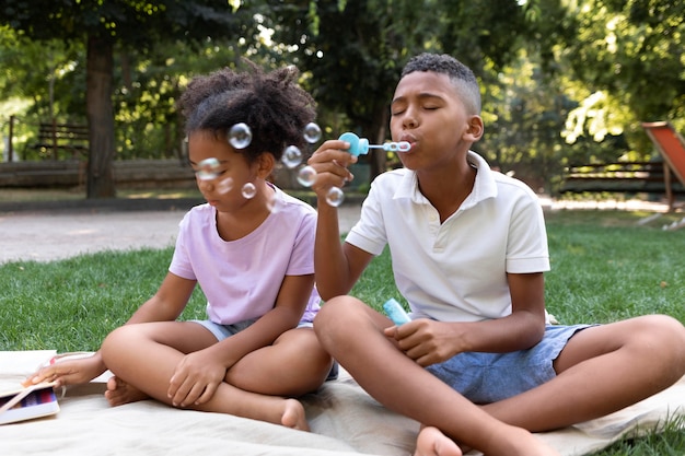 Niños de tiro completo haciendo pompas de jabón