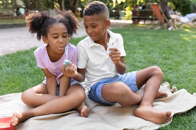 Niños de tiro completo haciendo pompas de jabón