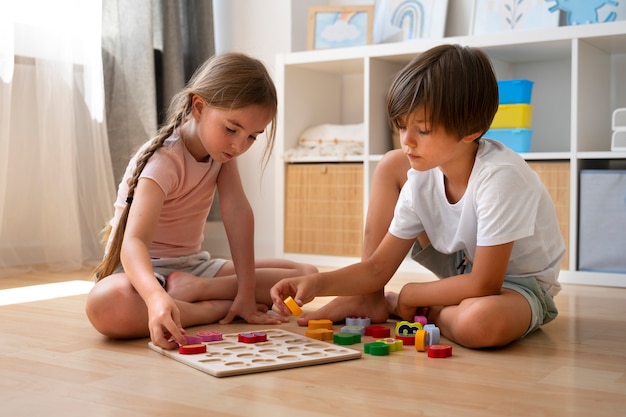 Niños de tiro completo haciendo rompecabezas juntos