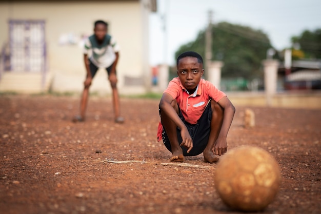 Niños de tiro completo jugando al fútbol al aire libre