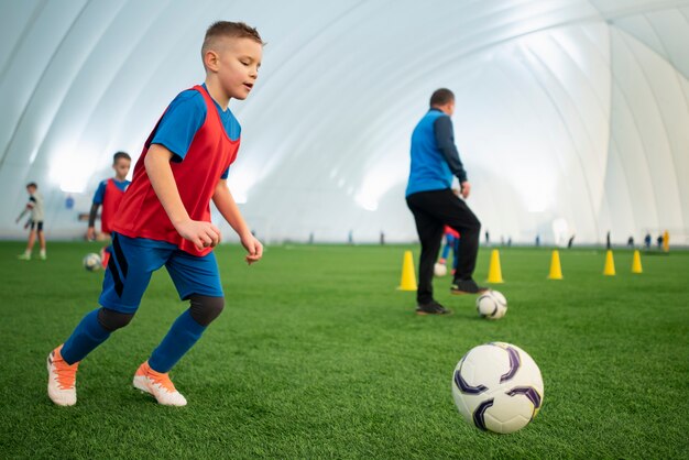 Niños de tiro completo jugando al fútbol en el campo