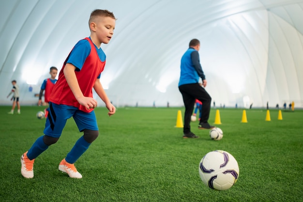 Niños de tiro completo jugando al fútbol en el campo