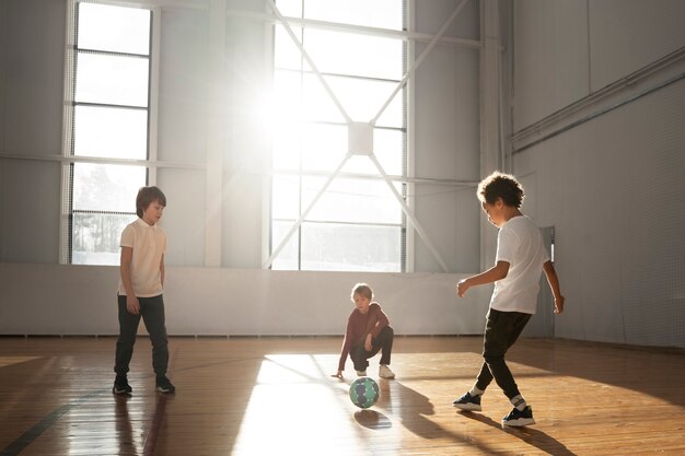 Niños de tiro completo jugando al fútbol juntos