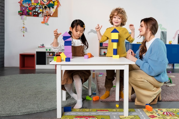 Niños de tiro completo jugando con formas de madera.