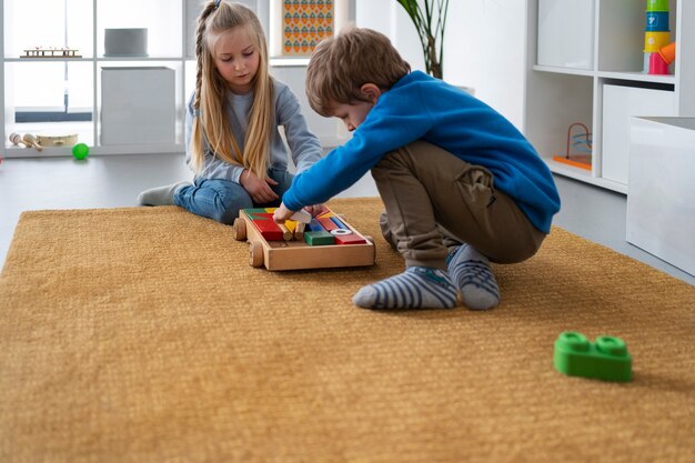 Niños de tiro completo jugando con juguetes de madera.