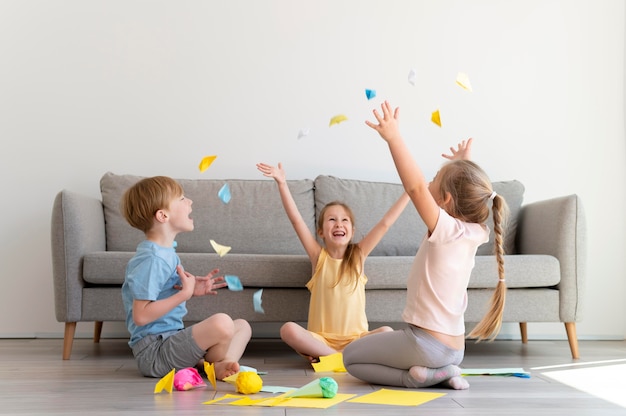 Niños de tiro completo jugando con papel