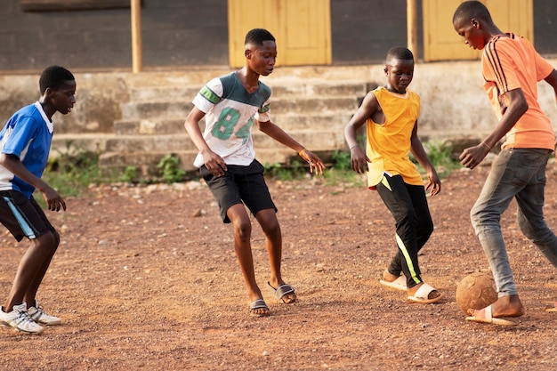 Niños de tiro completo jugando con pelota afuera