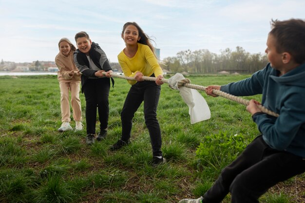 Niños de tiro completo jugando tira y afloja en el parque