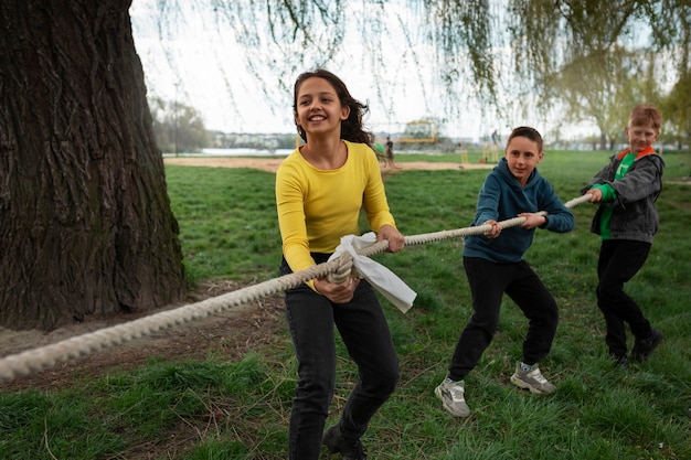 Foto gratuita niños de tiro completo jugando tira y afloja en el parque