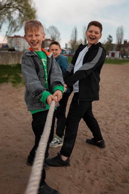 Niños de tiro completo jugando tira y afloja en la playa