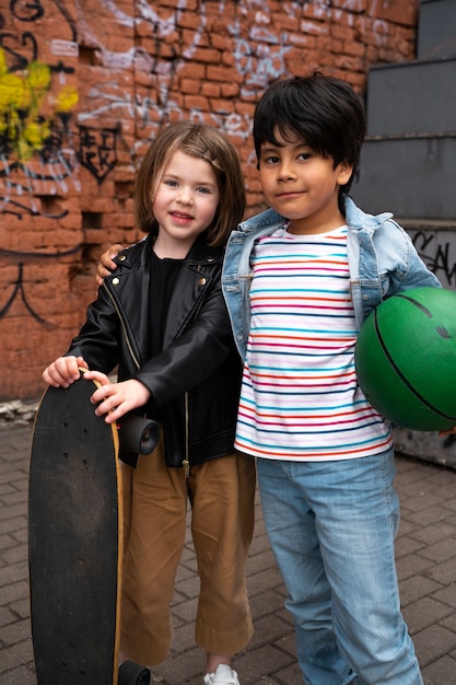 Niños de tiro completo con patineta y pelota.